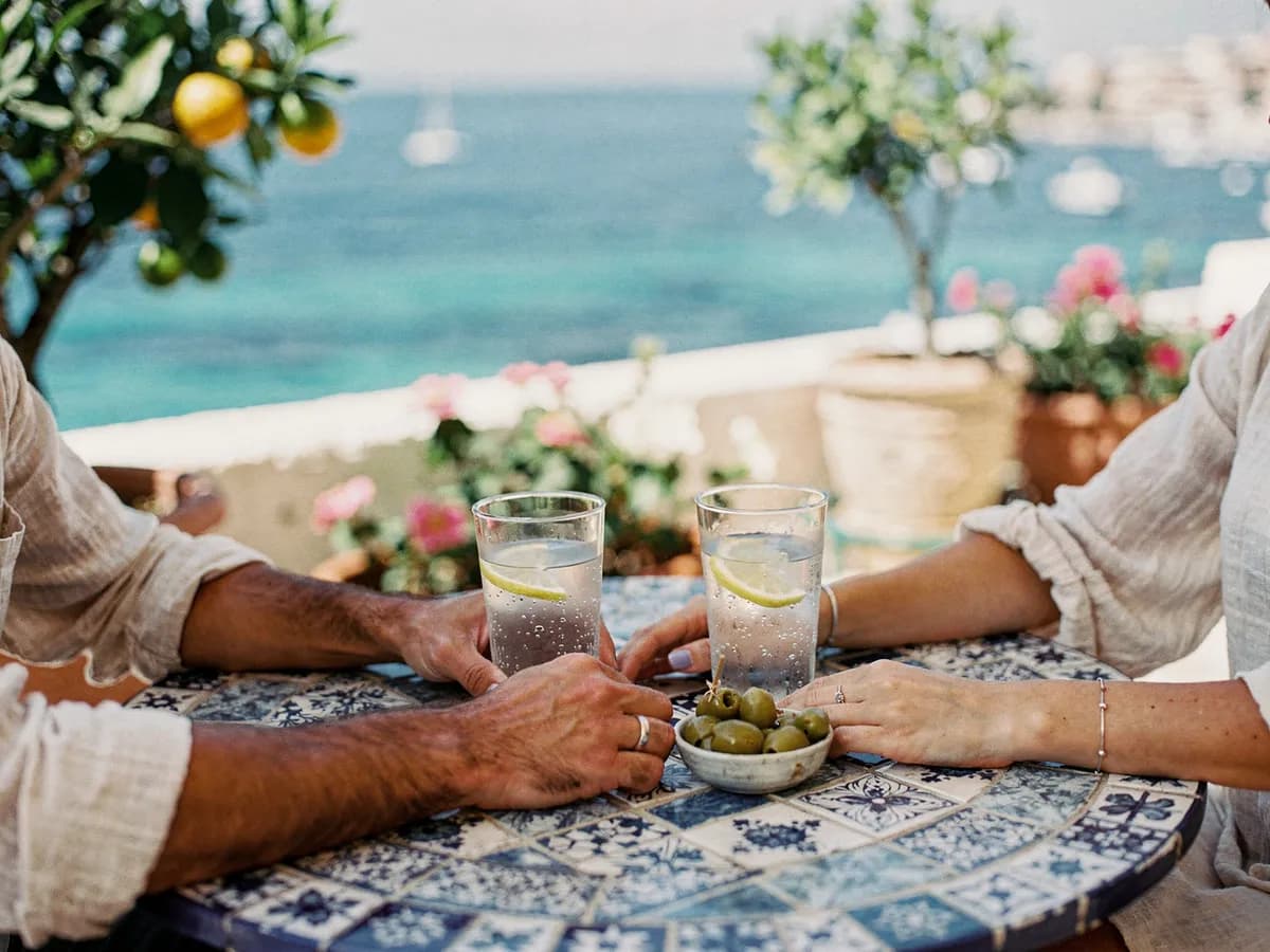 To hender ved siden av hverandre på et flislagt kafébord over havet